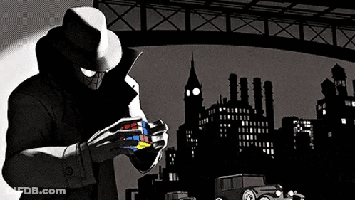 A Man In A Hat Is Holding A Rubik 'S Cube In His Hands . GIF
