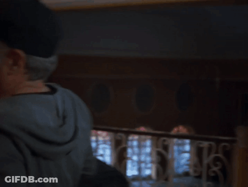 A Man In A Hat Is Hugging A Woman In A Room GIF