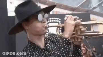 A Man In A Hat Is Playing A Trumpet . GIF