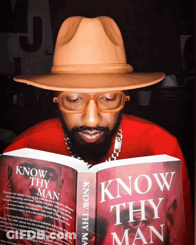 A Man In A Hat Is Reading A Book Titled Know Thy Man GIF