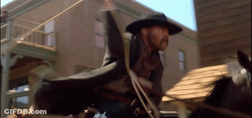 A Man In A Hat Is Riding A Horse GIF