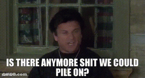 A Man In A Hat Is Sitting In Front Of A Window With The Words `` Is There Anymore Shit We Could Pile On '' . GIF