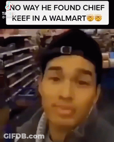 A Man In A Hat Is Standing In A Walmart And Looking At The Camera . GIF