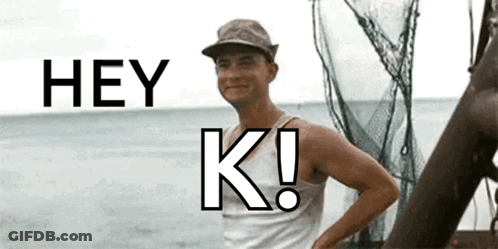 A Man In A Hat Is Standing In Front Of A Body Of Water And Says Hey K! GIF
