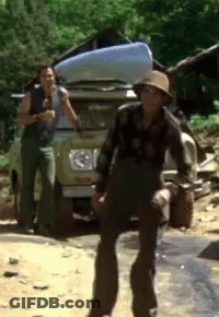 A Man In A Hat Is Standing In Front Of A Jeep With A Canoe On The Back GIF