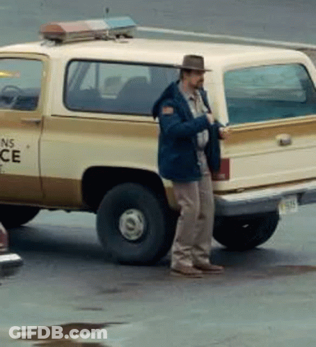 A Man In A Hat Is Standing Next To A Ns Police Truck GIF