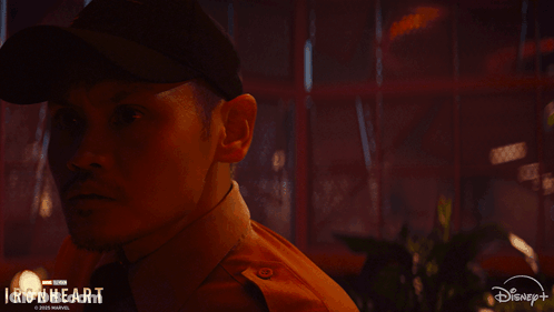 A Man In A Hat Is Standing Next To A Woman In A Disney + Ad GIF