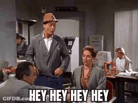 A Man In A Hat Is Standing Next To A Woman In An Office And Talking To Her . GIF