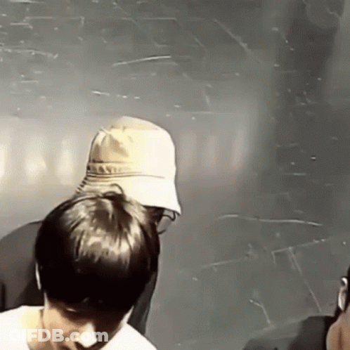 A Man In A Hat Is Standing Next To Another Man In A Room . GIF