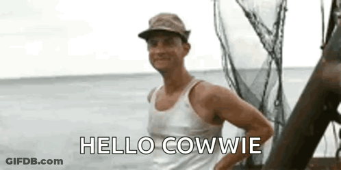 A Man In A Hat Is Standing On A Boat In The Ocean And Saying `` Hello Cowdie '' . GIF