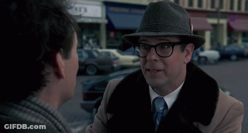 A Man In A Hat Is Talking To Another Man With The Word Bing Behind Him GIF