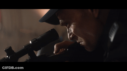 A Man In A Hat Looks Through A Telescope At Something GIF