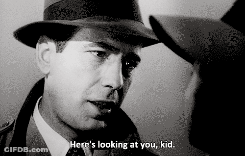A Man In A Hat Says " Here 'S Looking At You Kid " To Another Man GIF