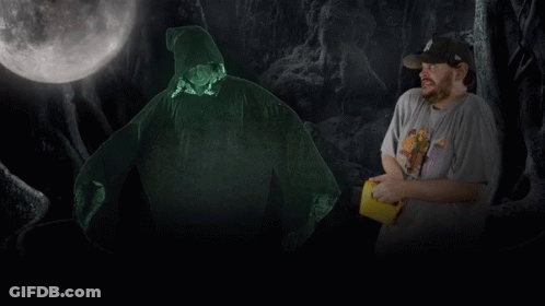 A Man In A Hat Stands In Front Of A Glowing Figure GIF