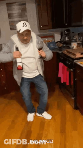 A Man In A Hat With The Letter B On It Is Holding A Bottle Of Wine And A Glass . GIF