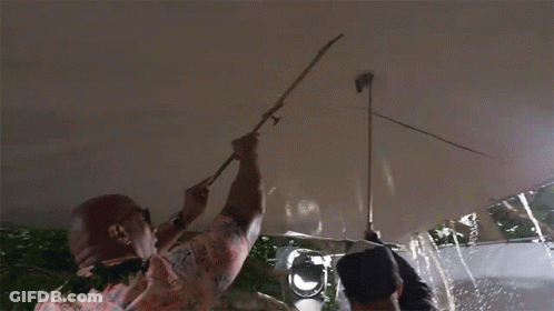 A Man In A Hawaiian Shirt Is Holding A Stick Up To A Ceiling GIF