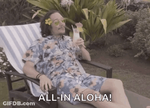 A Man In A Hawaiian Shirt Is Sitting In A Chair Drinking A Cocktail And Saying All In Aloha GIF