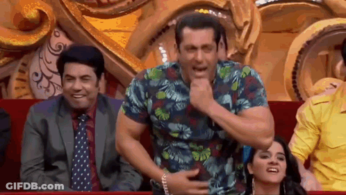 A Man In A Hawaiian Shirt Is Sitting In A Theatre With Other People And Making A Funny Face . GIF