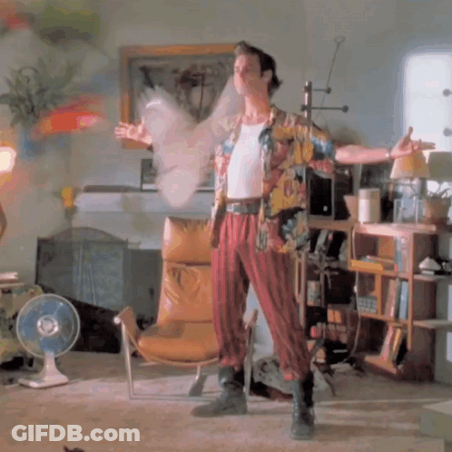 A Man In A Hawaiian Shirt Is Standing In A Room With A Fan GIF