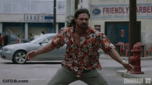 A Man In A Hawaiian Shirt Is Standing In Front Of A Fire Hydrant On A City Street . GIF