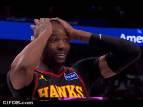 A Man In A Hawks Jersey Is Holding His Head GIF