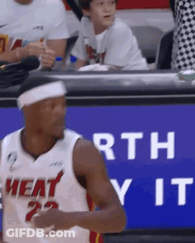 A Man In A Heat Jersey Is Standing In Front Of A Sign That Says Worth It . GIF