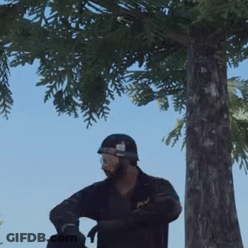 A Man In A Helmet And Goggles Is Standing In Front Of A Tree . GIF