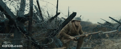 A Man In A Helmet Holding A Rifle In A Field GIF
