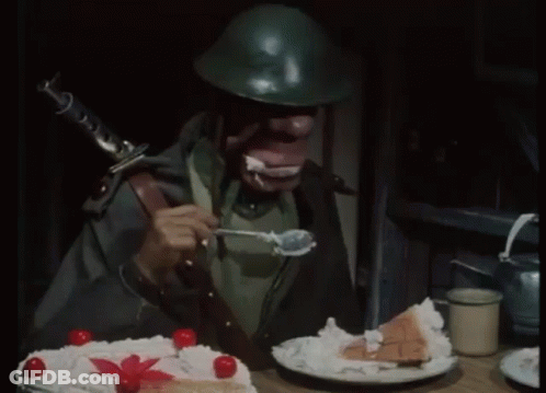 A Man In A Helmet Is Eating A Piece Of Cake With Whipped Cream GIF