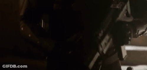 A Man In A Helmet Is Holding A Gun In His Hand . GIF
