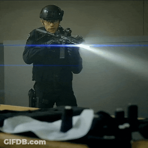 A Man In A Helmet Is Holding A Gun GIF