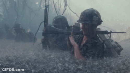 A Man In A Helmet Is Holding A Rifle In The Water GIF