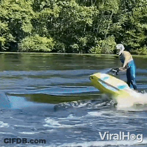 A Man In A Helmet Is Riding A Jet Ski In A Lake . GIF