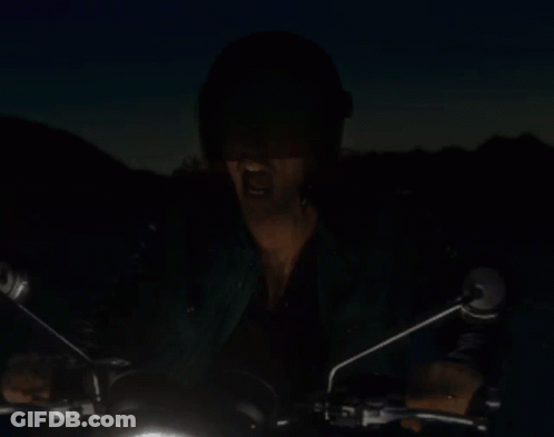 A Man In A Helmet Is Riding A Motorcycle In The Dark GIF