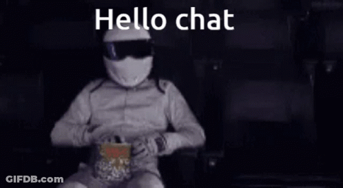 A Man In A Helmet Is Sitting In A Chair Eating Popcorn And Talking On A Cell Phone . GIF