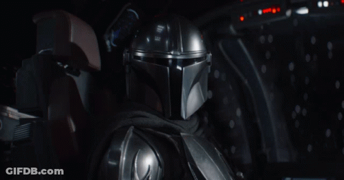 A Man In A Helmet Is Sitting In A Dark Room And Says Grogu GIF