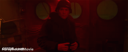 A Man In A Helmet Is Standing In A Dark Room With The Hashtag #Greyhoundmovie Below Him GIF