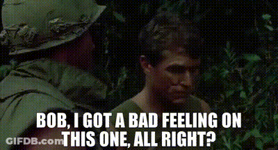 A Man In A Helmet Is Talking To Another Man In The Woods . GIF