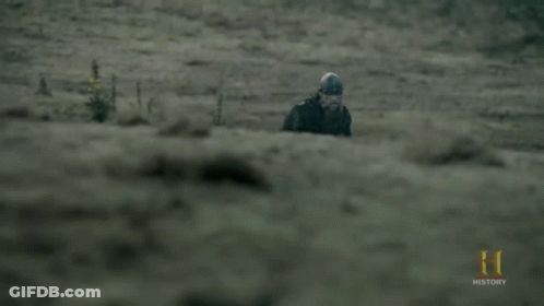 A Man In A Helmet Is Walking In A Field With A History Logo In The Corner GIF