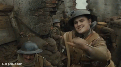 A Man In A Helmet Looks At His Watch In A Trench GIF
