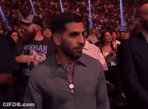 A Man In A Herman Shirt Stands In A Crowd Of People GIF