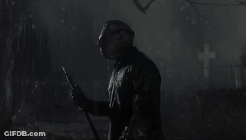 A Man In A Hockey Mask Is Holding A Knife In The Rain GIF