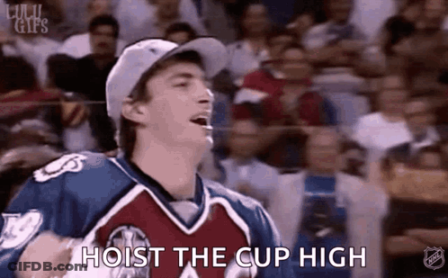 A Man In A Hockey Uniform Is Holding A Hockey Puck In Front Of A Crowd And Says `` Hoist The Cup High '' . GIF