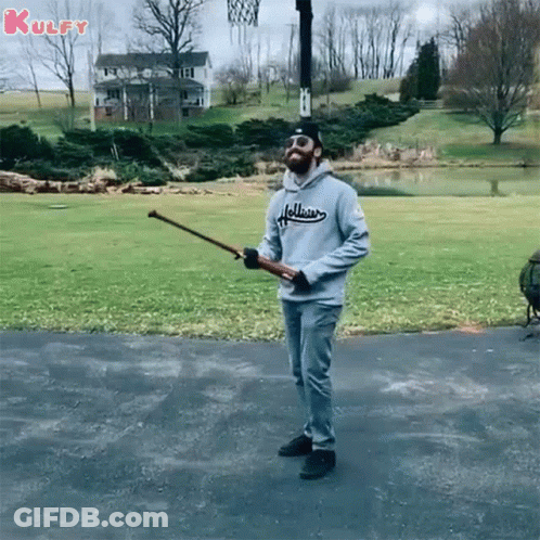 A Man In A Hollister Sweatshirt Is Holding A Baseball Bat GIF