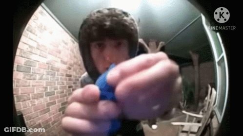 A Man In A Hood Is Holding A Blue Object In His Hand . GIF