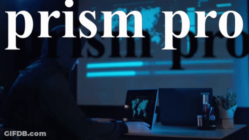 A Man In A Hood Is Using A Laptop In Front Of A Sign That Says Prism Pro GIF
