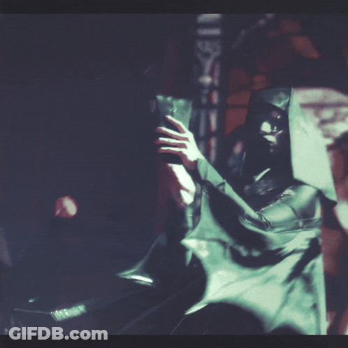 A Man In A Hooded Cloak Is Holding A Sword GIF