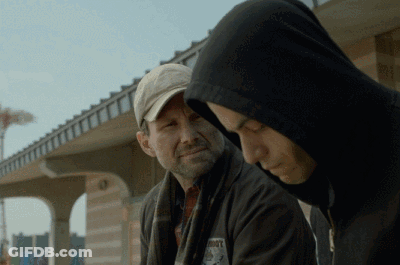 A Man In A Hooded Jacket Has A Patch On His Jacket That Says ' Roots ' On It GIF