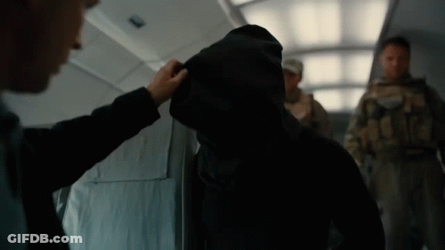 A Man In A Hooded Jacket Is Being Touched By Another Man In A Suit GIF