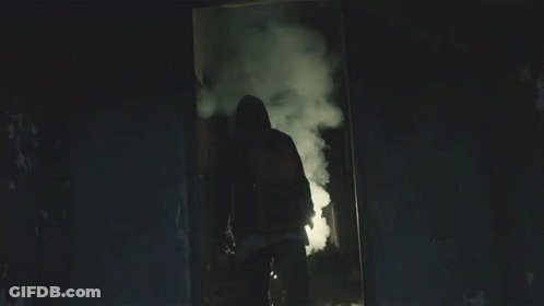 A Man In A Hooded Jacket Is Holding A Light GIF